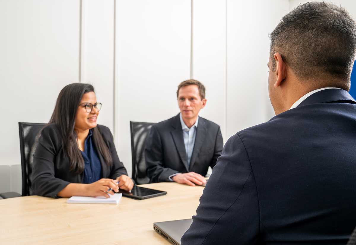 Two consultants meeting with a client around a table to discuss AI testing