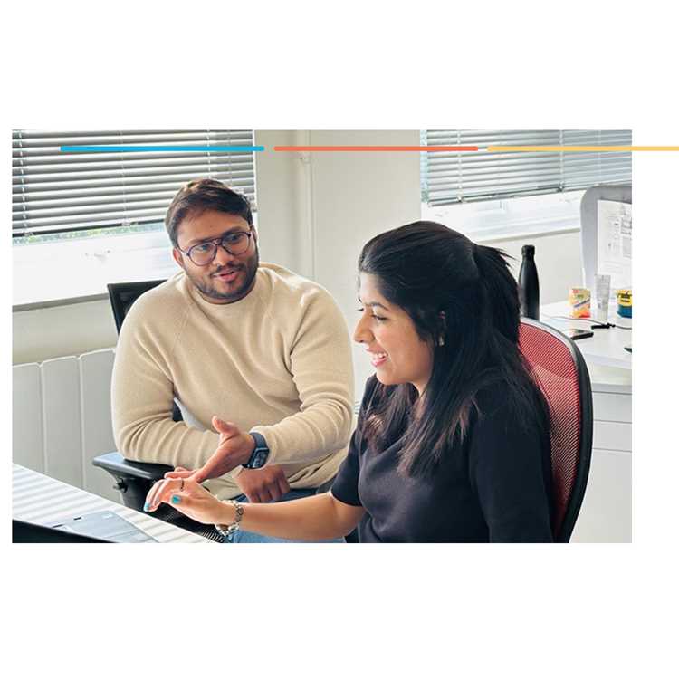 Two colleagues talking at a desk in an office
