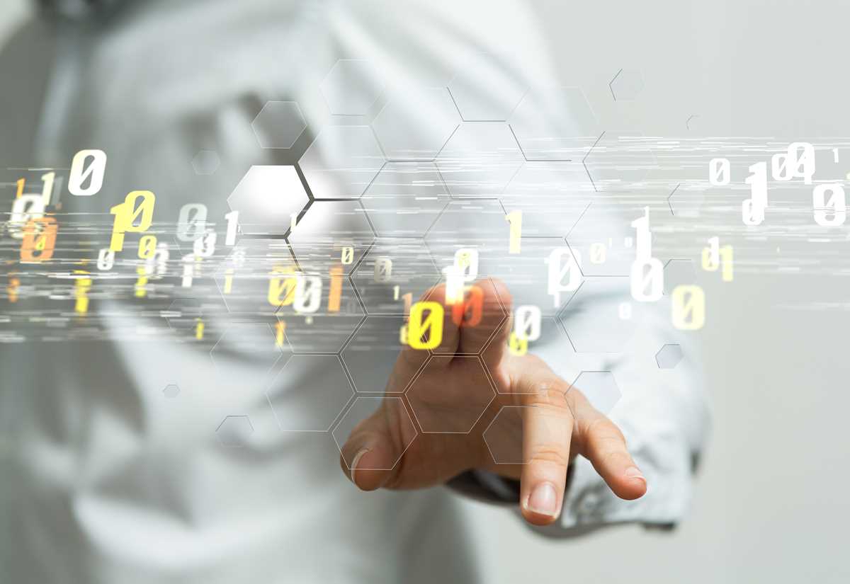 A person touching a digital display of glowing numbers and hexagons