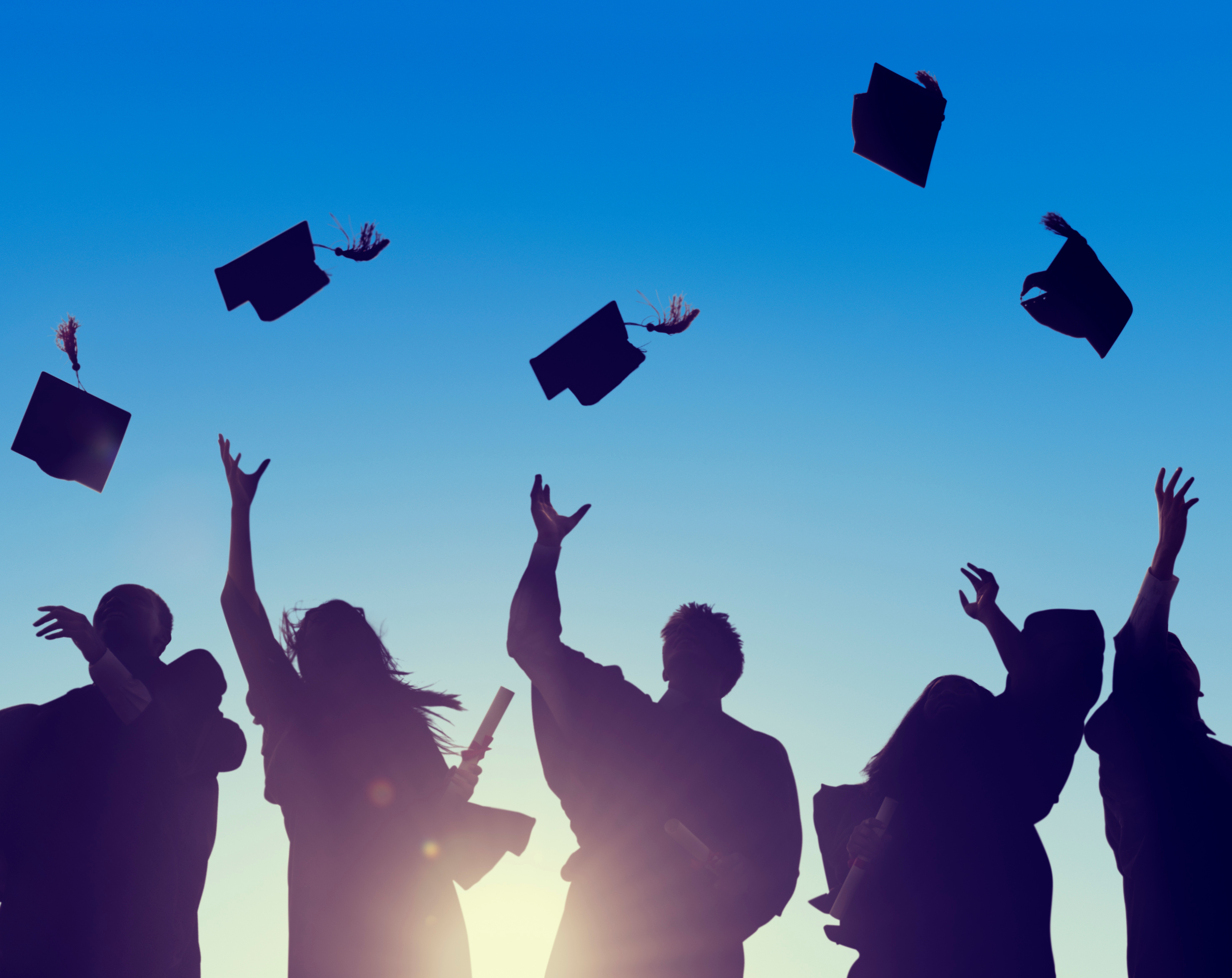 university students throwing graduation caps in the air