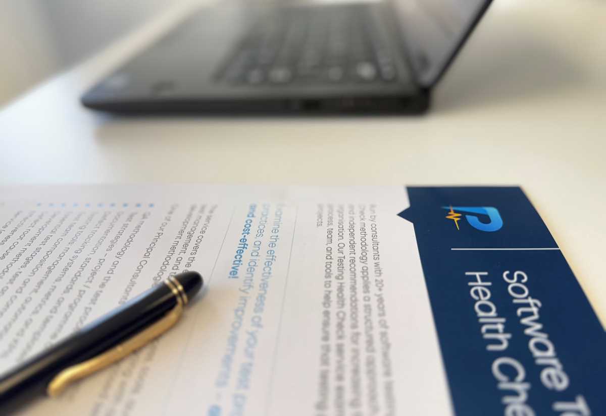 Printed Software Testing Health Check report with a fountain pen resting on it, next to a laptop